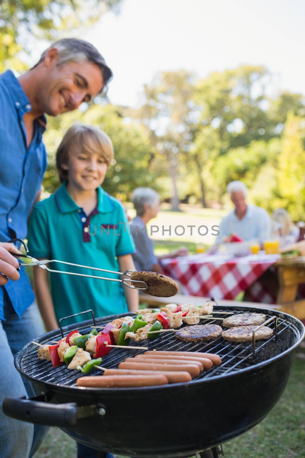 Happy father doing barbecue with his son on a sunny day