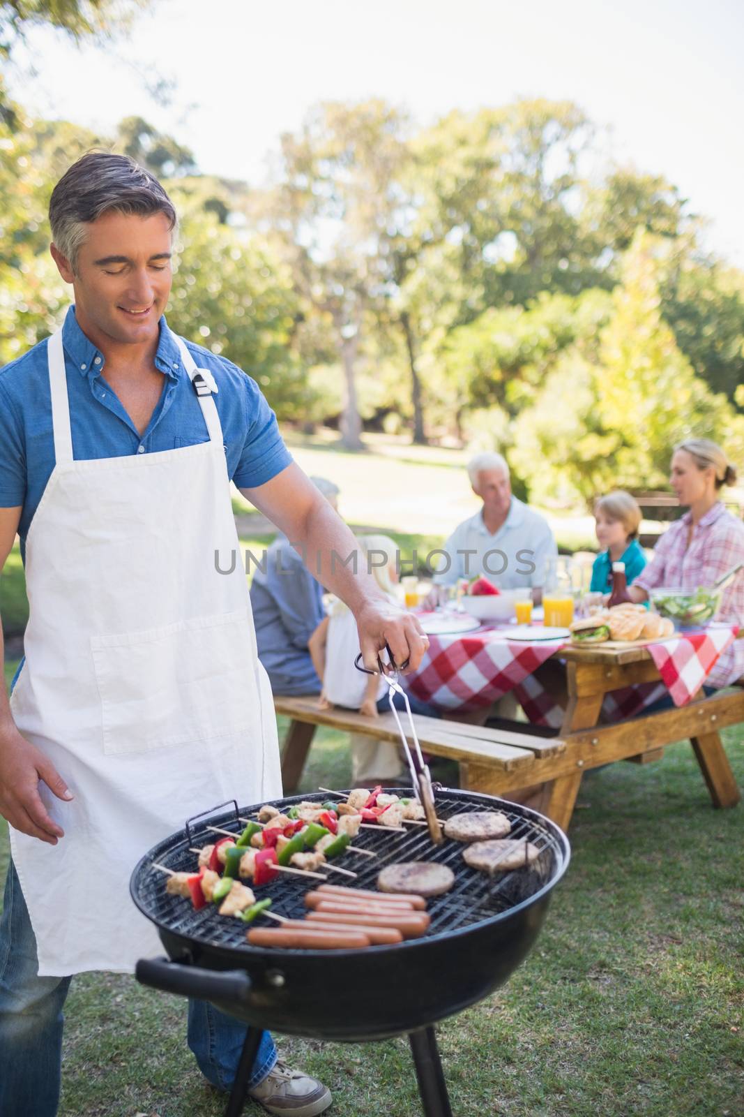 Happy man doing barbecue for his family in a sunny day