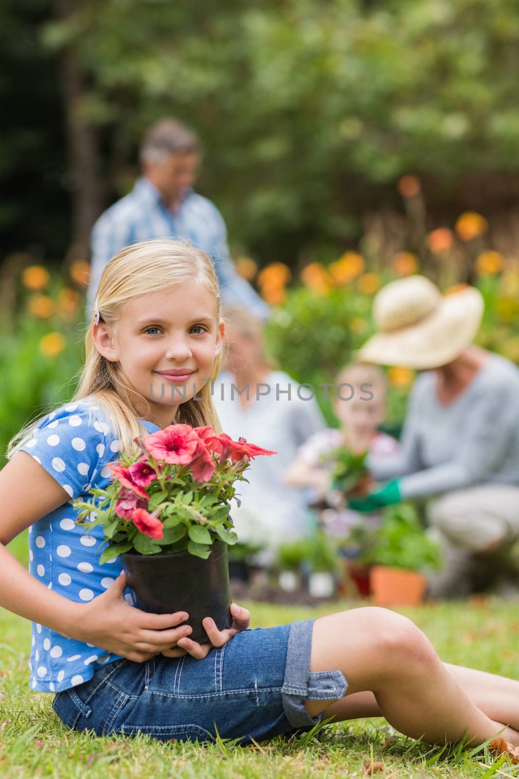 Young girl sitting with flower pot on a sunny day 