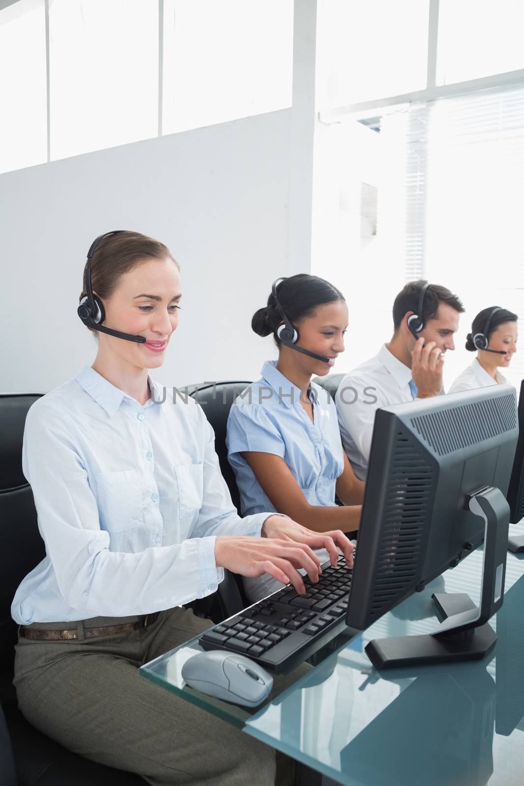 Business people with headsets using computers in office