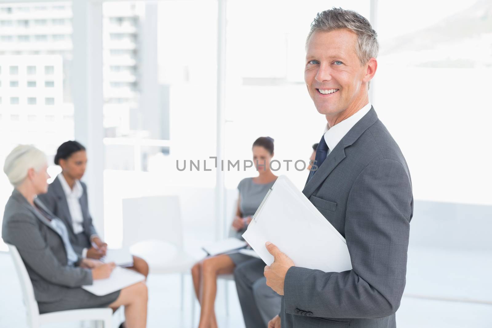 businessman writing notes with colleagues behind at office