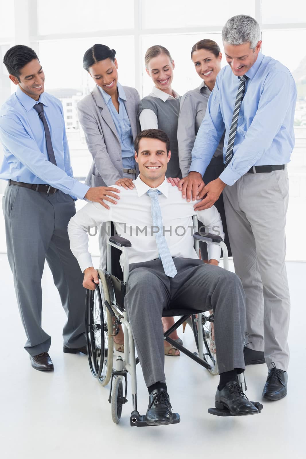 Business people supporting their colleague in wheelchair in office 
