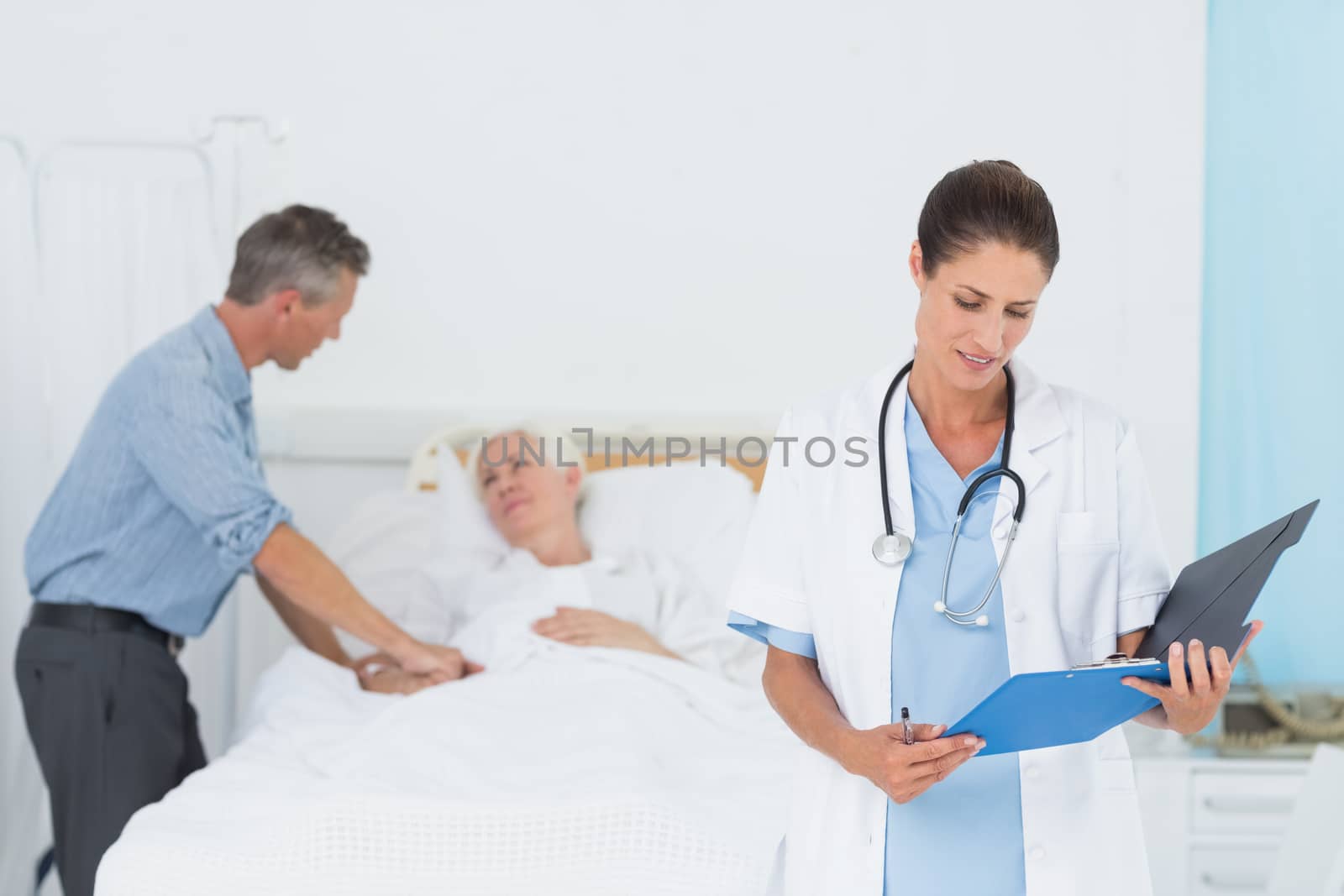 Doctor explaining report to female patient and husband by Wavebreakmedia
