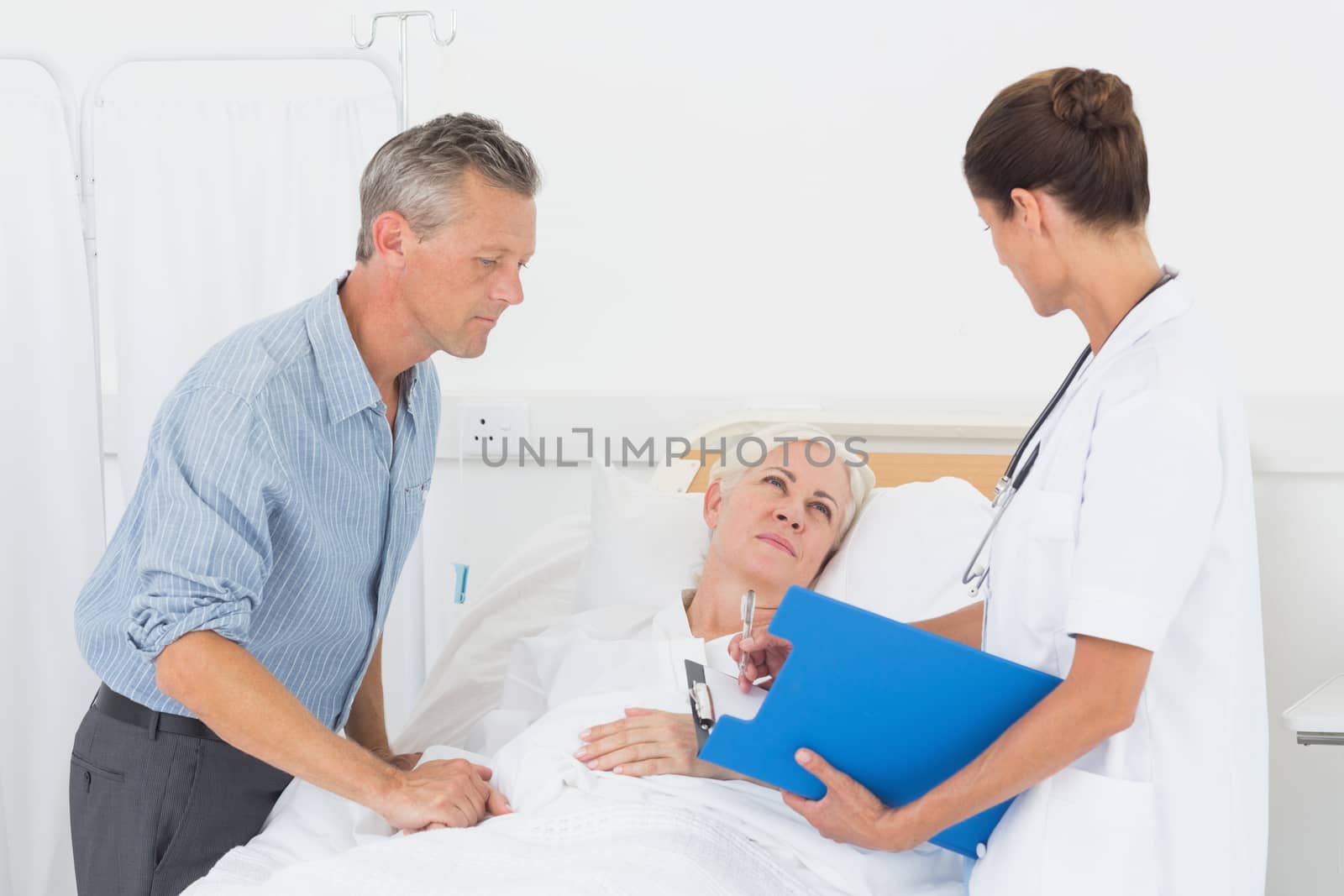 Doctor explaining report to female patient and husband by Wavebreakmedia