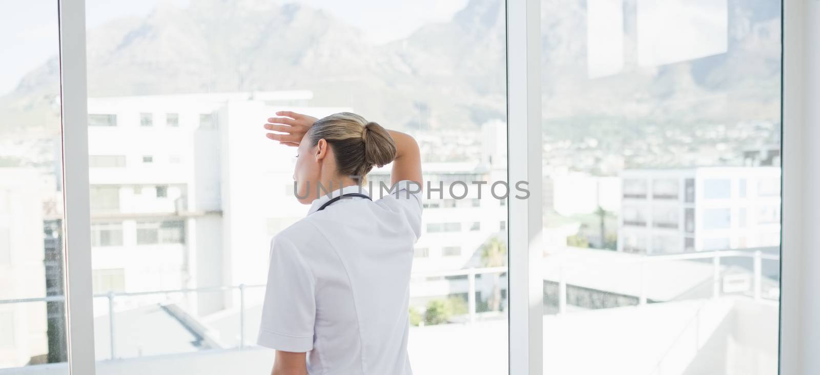 Wear view of confident female doctor looking through windows in hospital