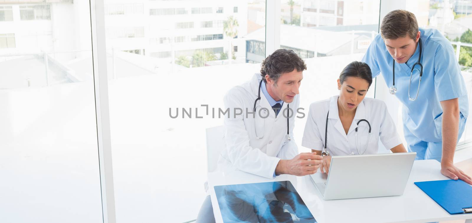 Team of doctors working on laptop computer in medical office
