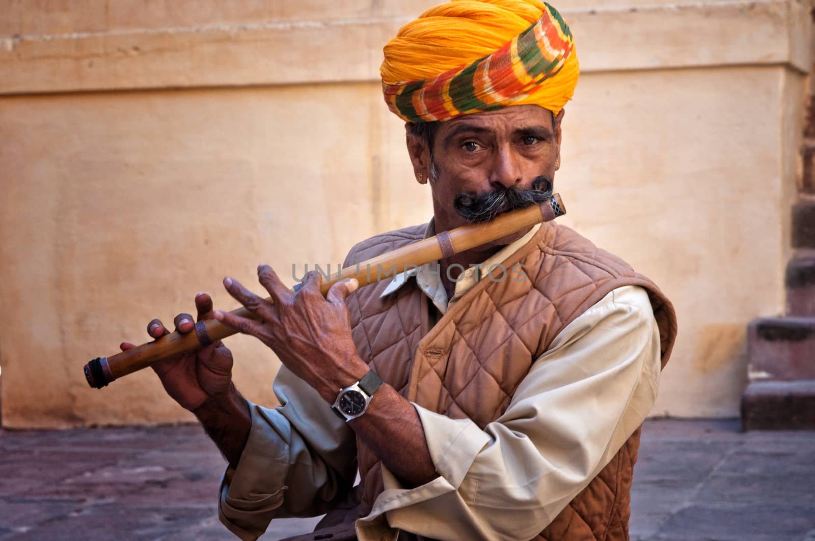 Man wearing turban playing on the flute in the Jodhpur fort, India. February 28, 2013