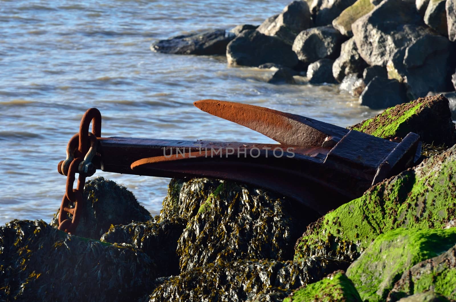 Large iron anchor on rocks