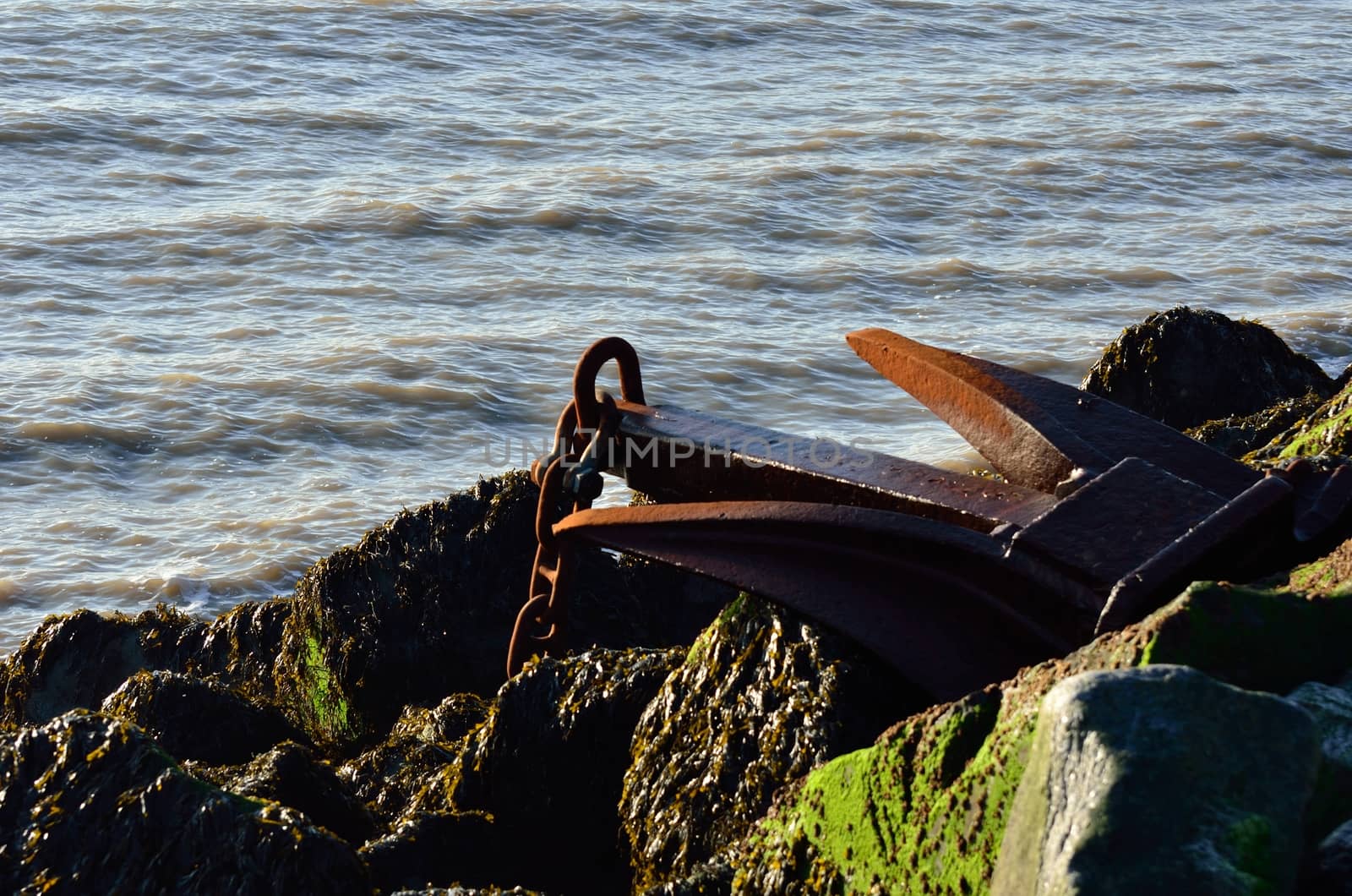 Large rusty anchor on top of group of rocks