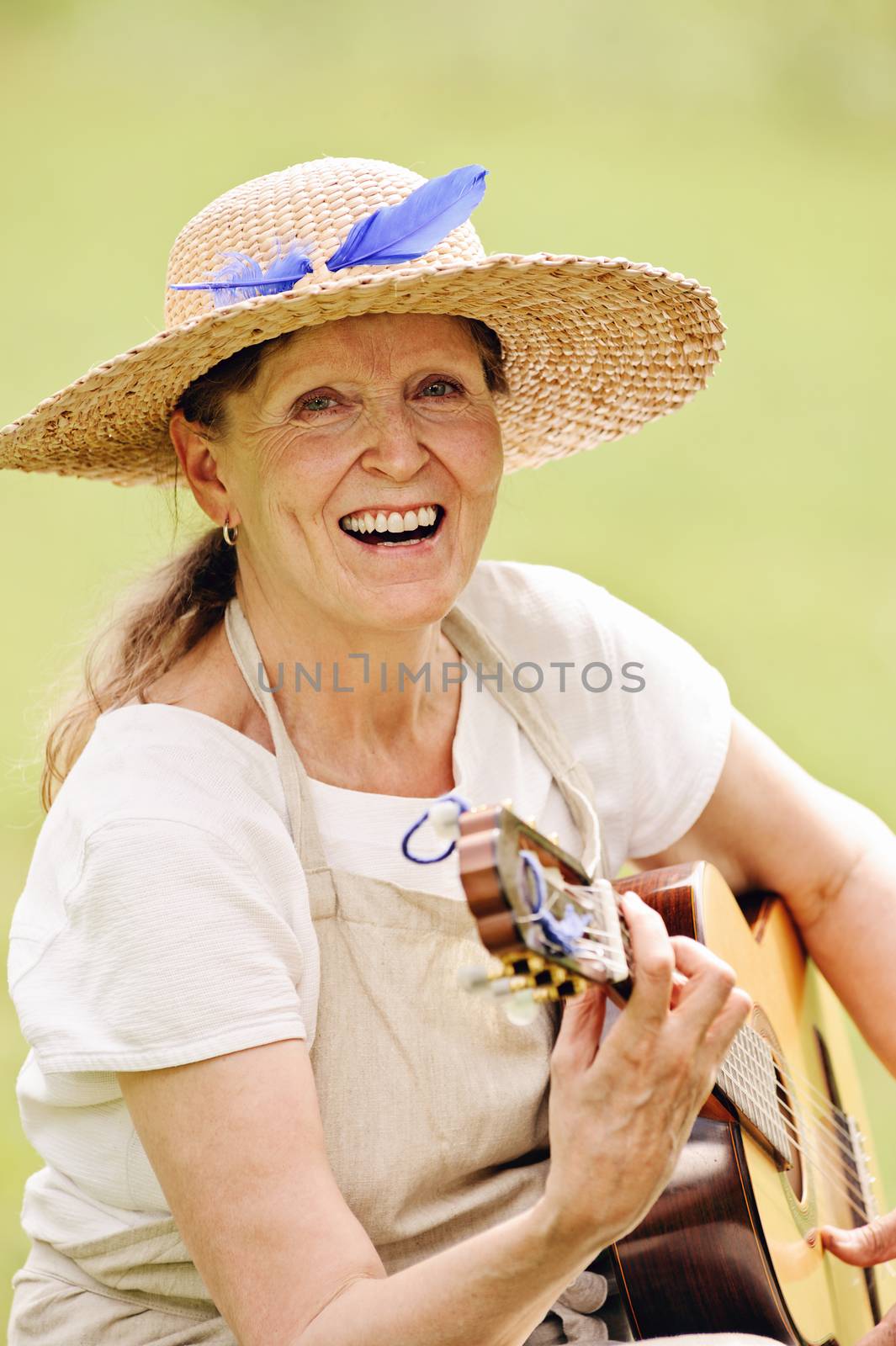 happy senior woman playing guitar outdoors. Digital filters have been used to create a nostalgic retro effect