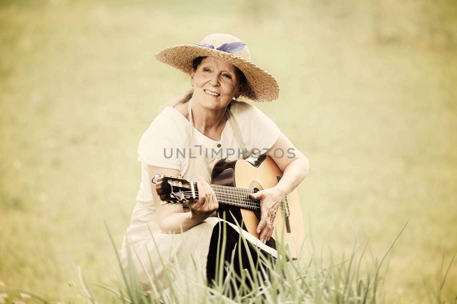 happy senior woman playing guitar outdoors. Digital filters have been used to create a nostalgic retro effect