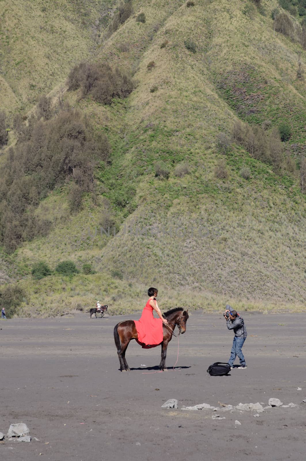 MOUNT BROMO, JAVA INDONESIA - JUNE 28, 2014: Undefined model posing on a horse under the Bromo massif. by johnnychaos