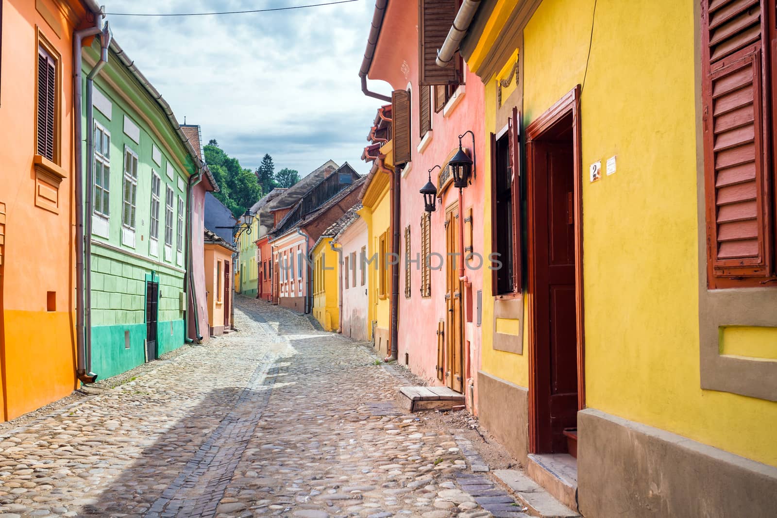 Sighisoara, Romania - June 23, 2013: Stone paved old streets with colored houses from Sighisoara fortresss, Transylvania, Romania