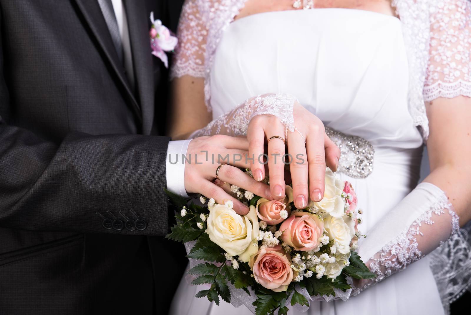 Hands of the newlyweds with wedding bouquet. horizontal shot