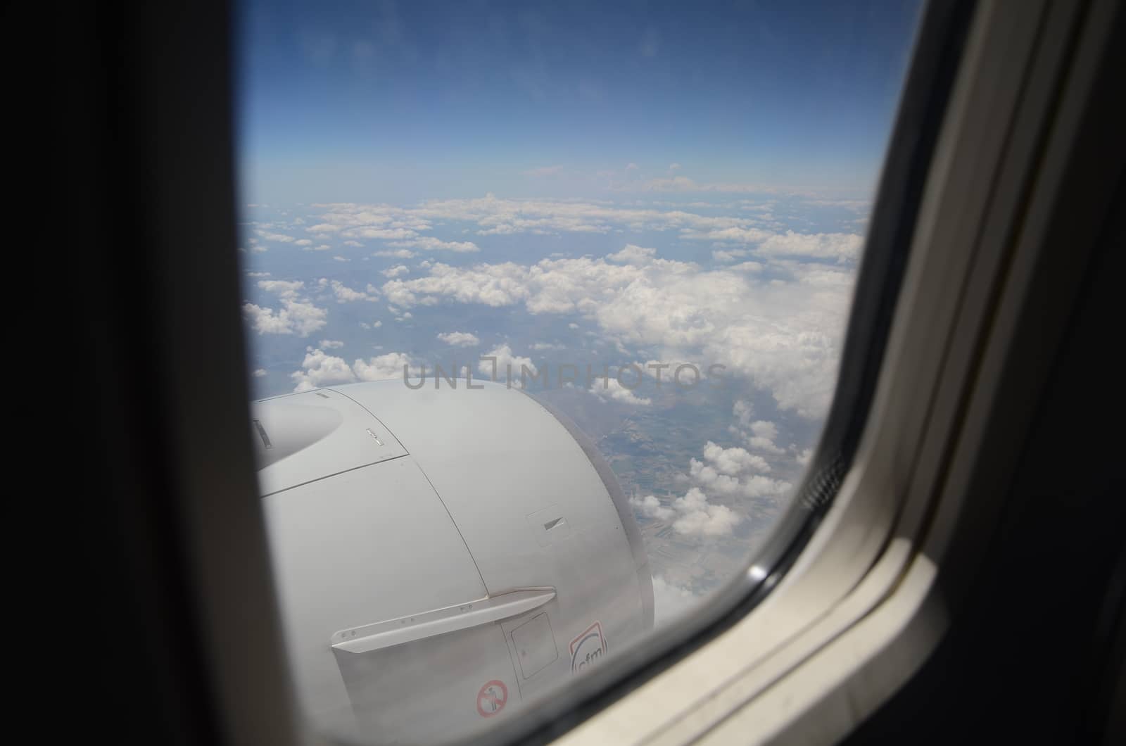 Airplane window with a view of sky and clouds.