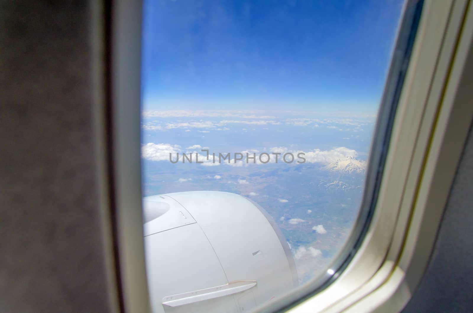 Airplane window with a view of sky and clouds.