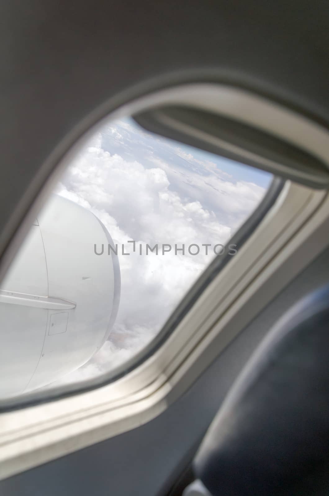 Airplane window with a view of sky and clouds.