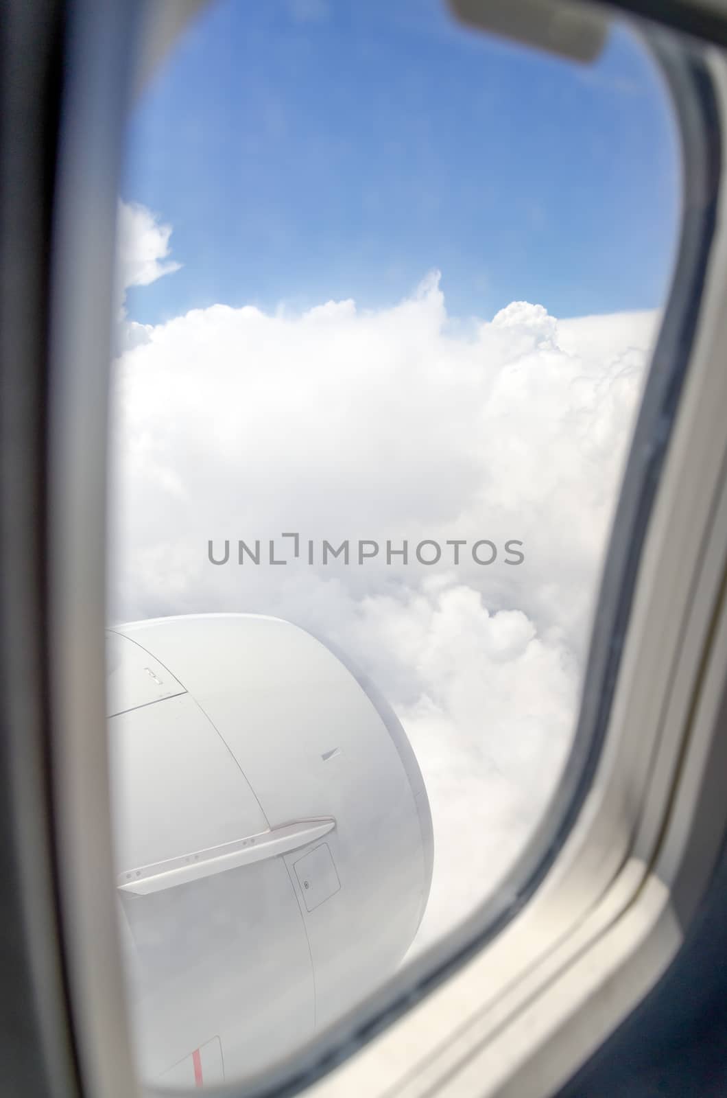 Airplane window with a view of sky and clouds.