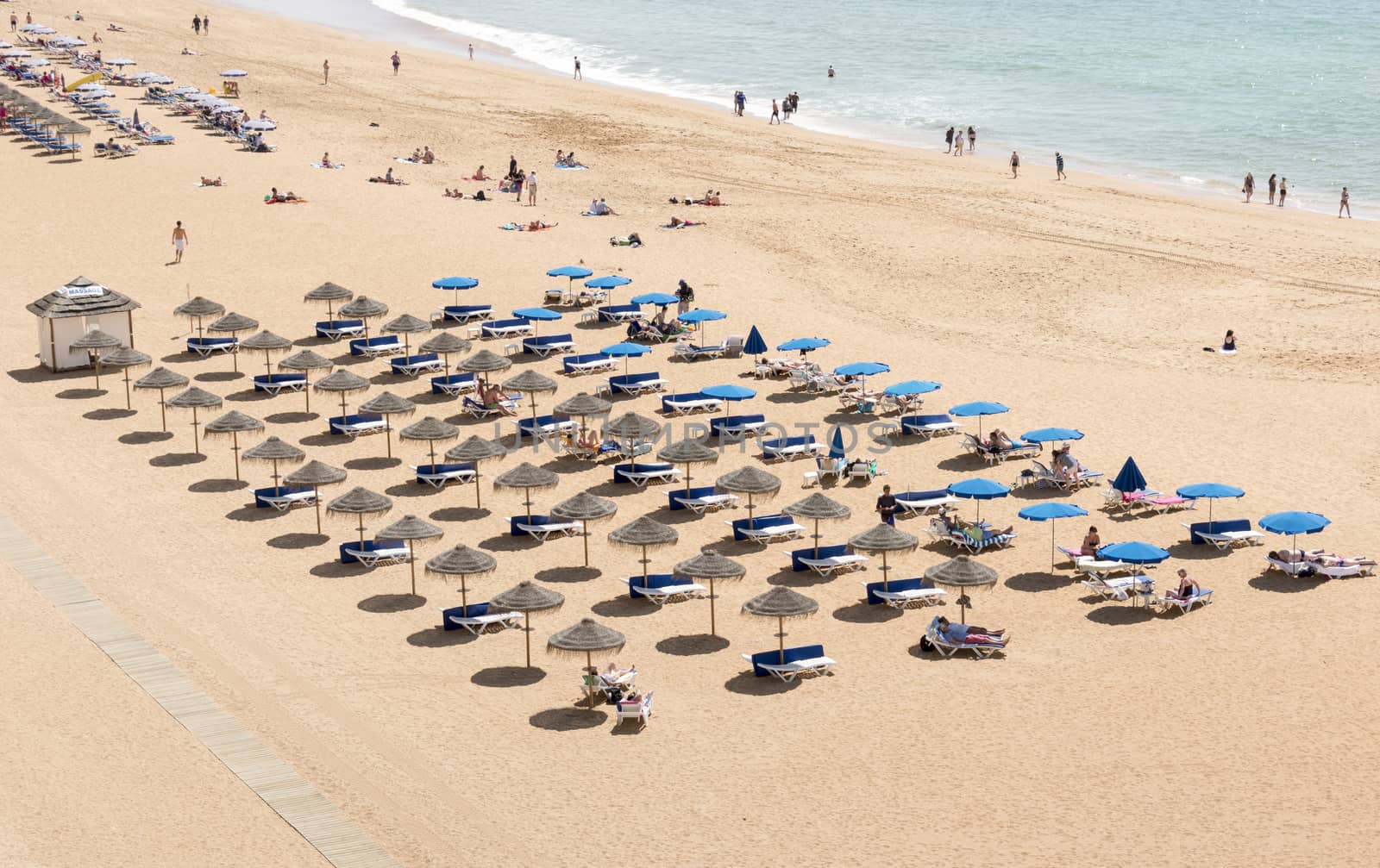 ALBUFEIRA, PORTUGAL - APRIL 23: View of crowded Falesia beach at the midday in the summer mediterranean resort Albufeira on April 23, 2015. This town is a part of famous tourist region Algarve.