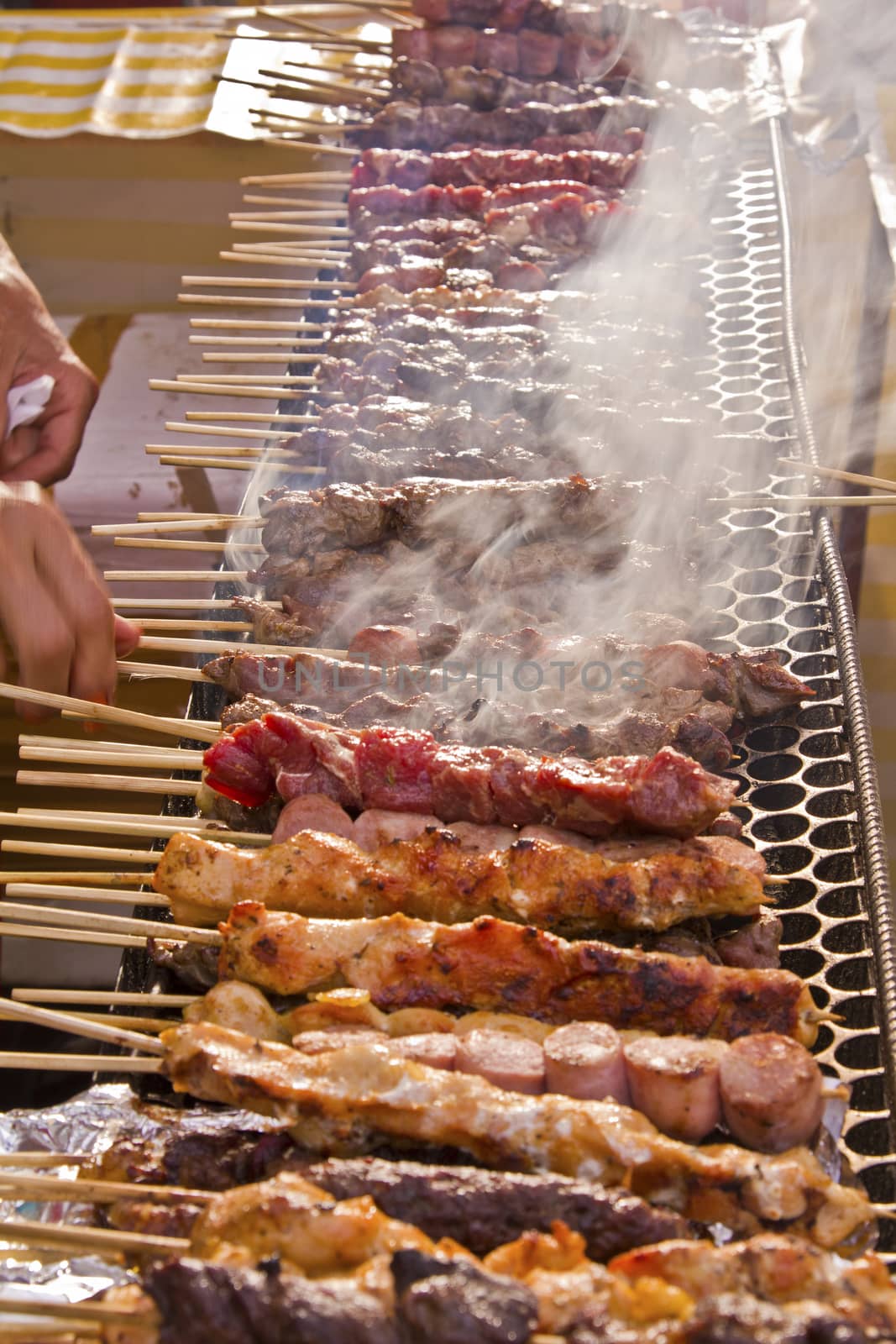 Street fair tend of skewered meat with smoke