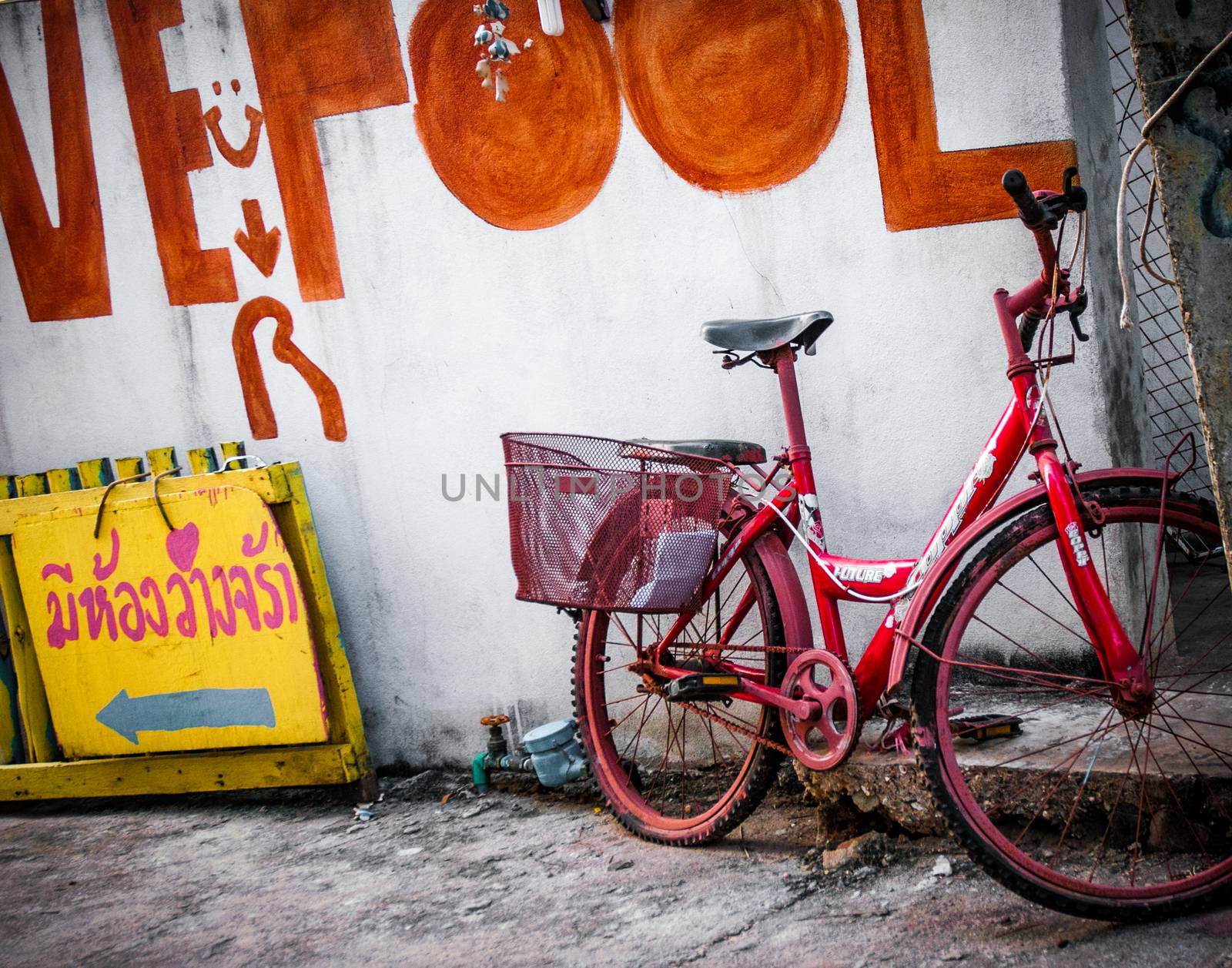 Old colourful red bike in Thailand with yellow sign