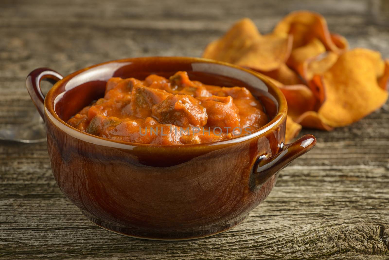 Bowl of homemade steak chili on a rustic background.