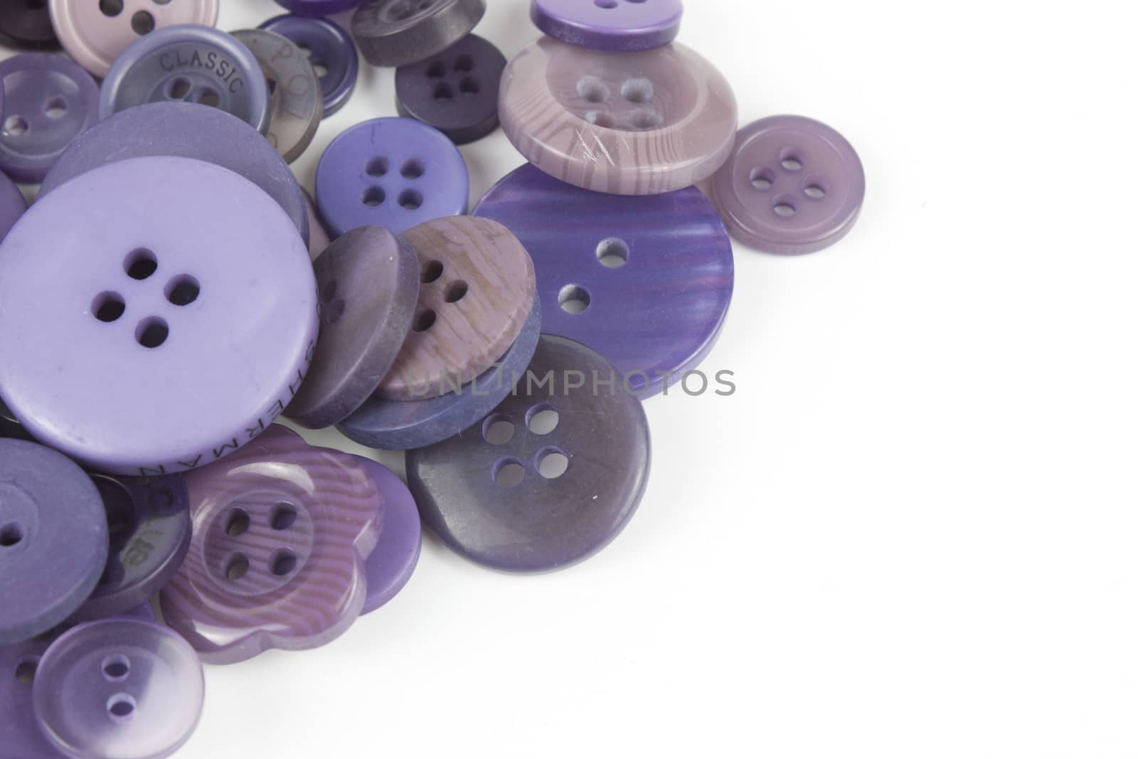 Close up of various purple button scattered on a white surface.