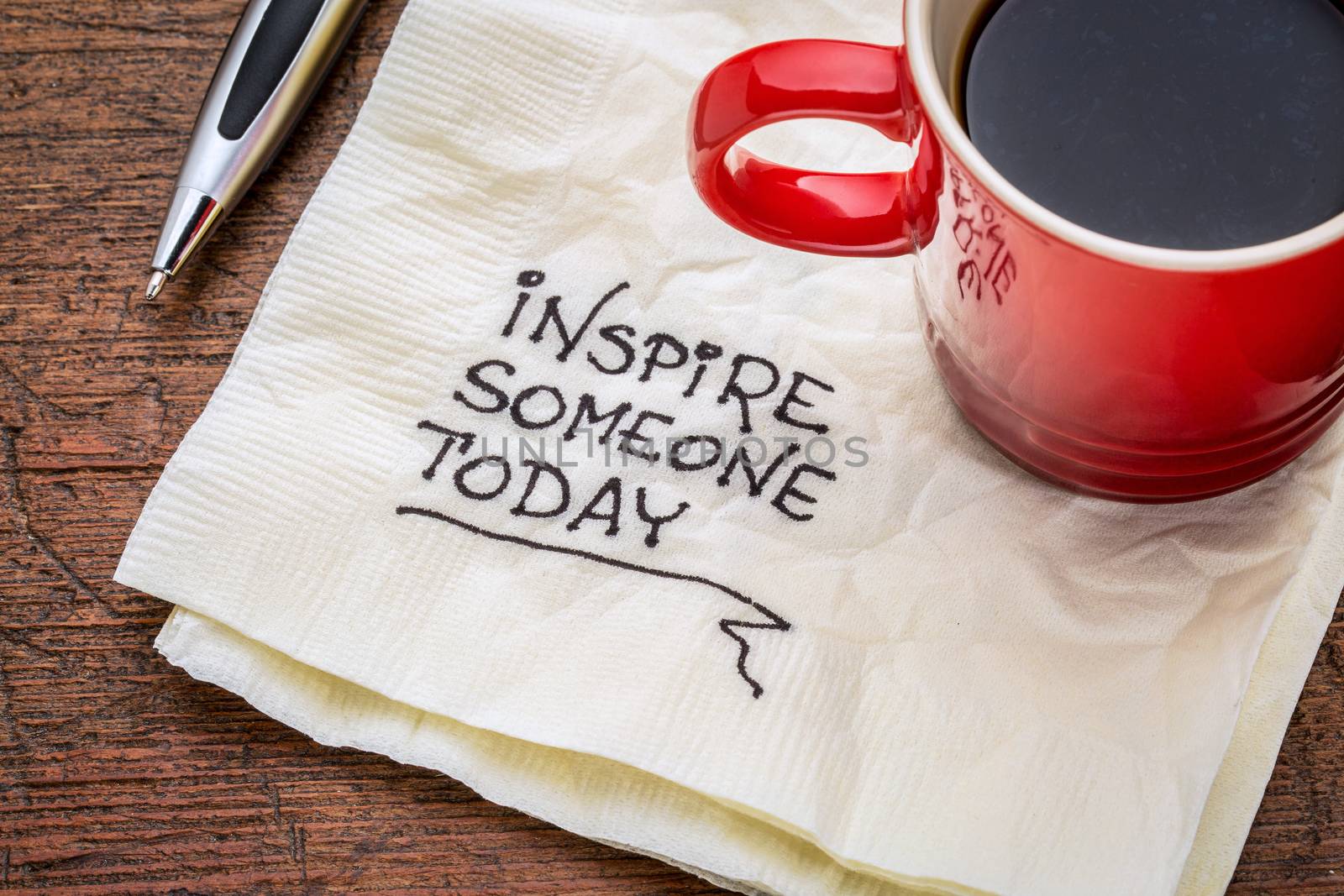 inspire someone today - motivational handwriting on a napkin with cup of coffee