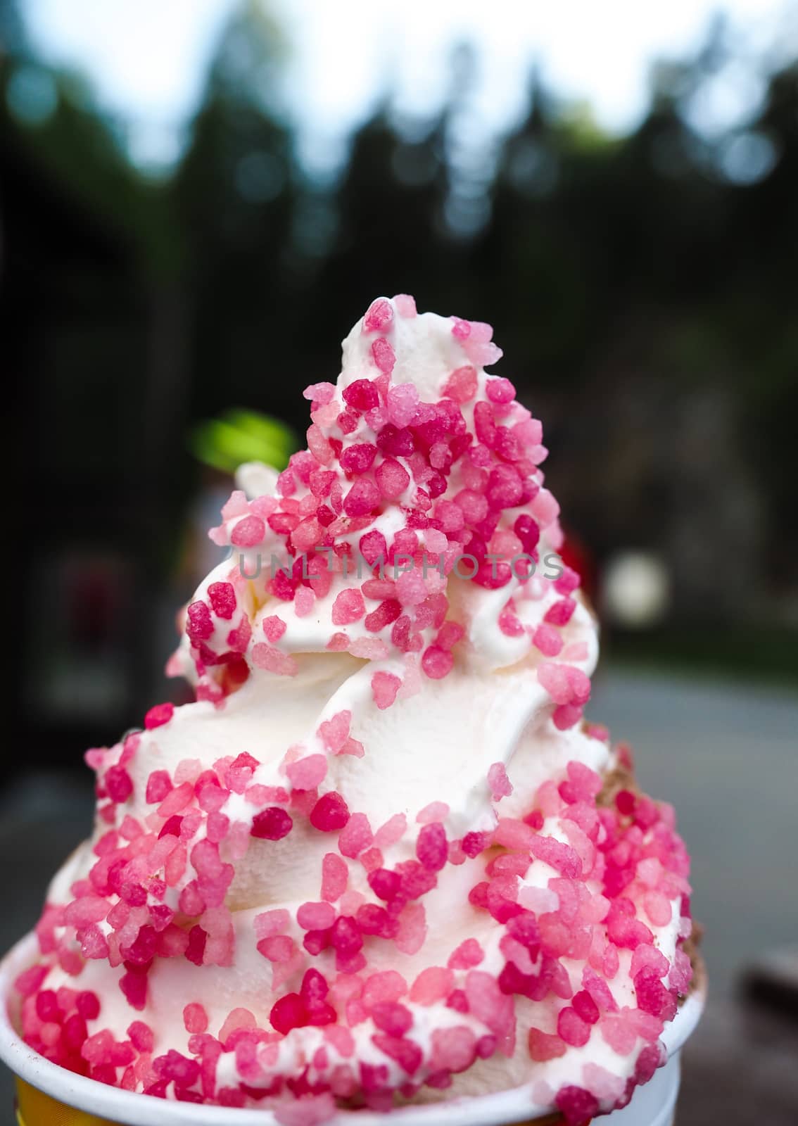 Closeup of soft serve ice cream with fresh pink frizzle outdoors by Arvebettum