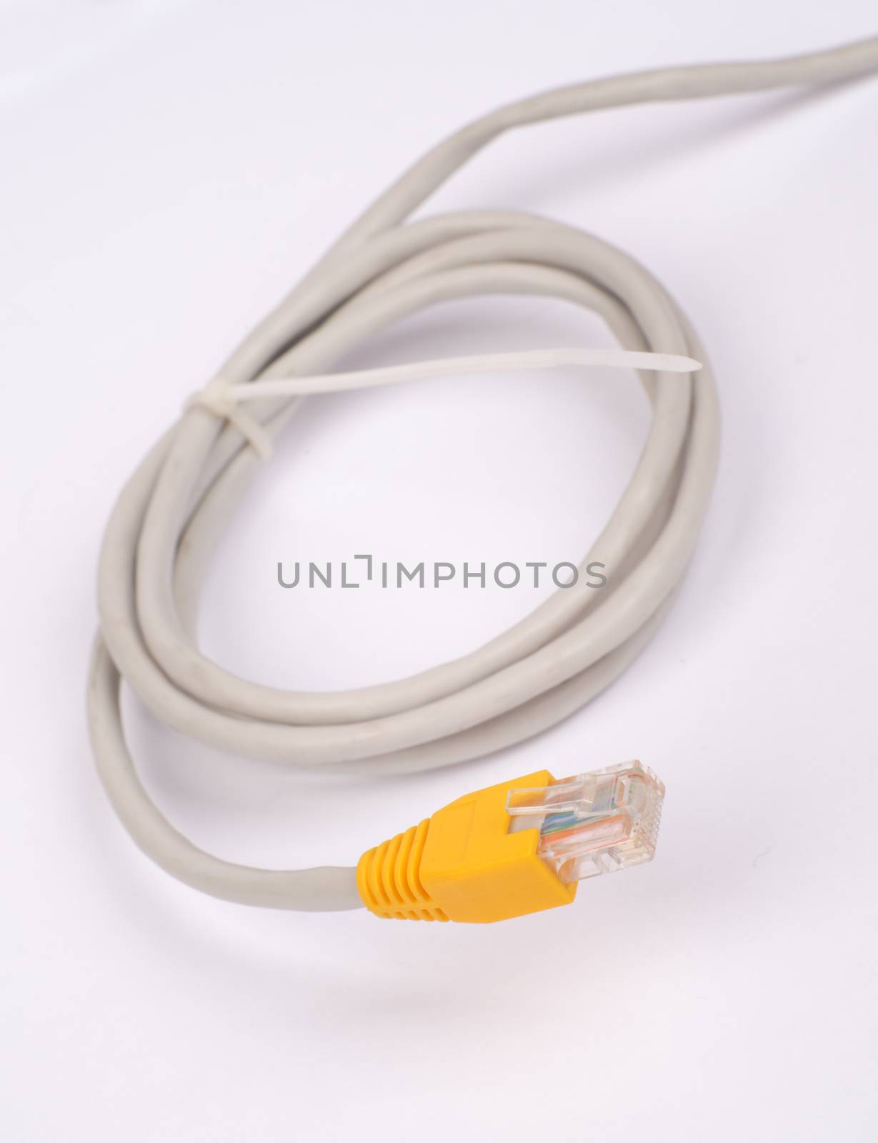 Twisted yellow computer cable on isolated white background, close up view