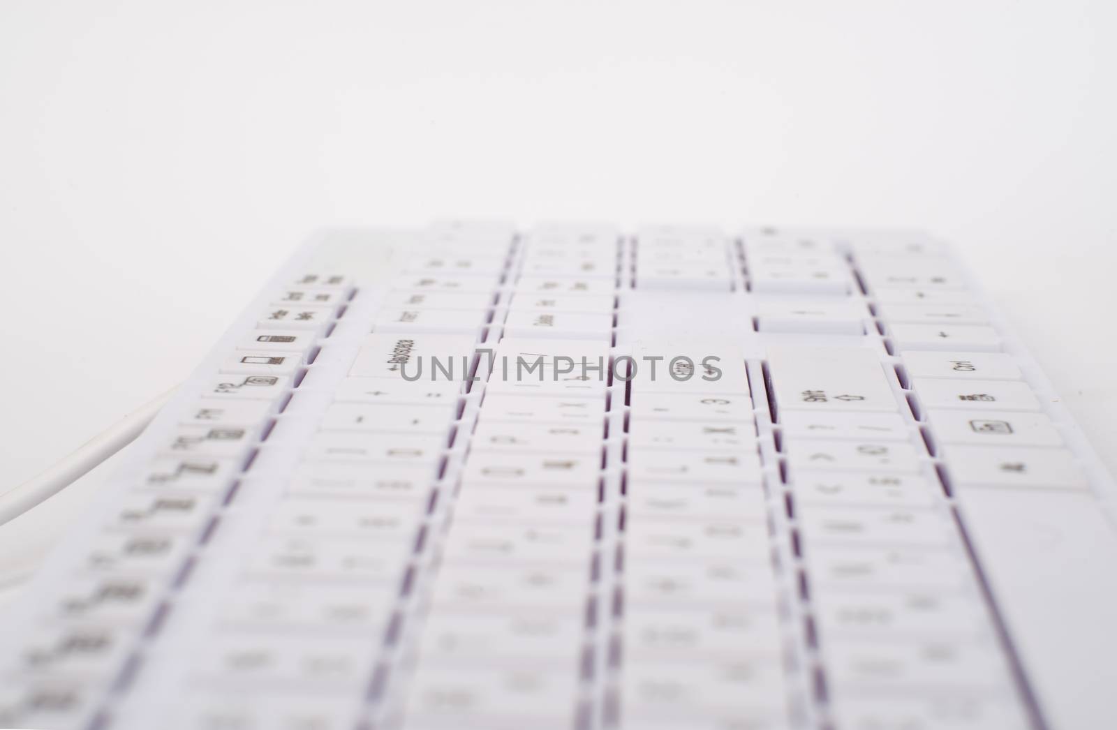 White computer keyboard with wire on isolated white background, close up view