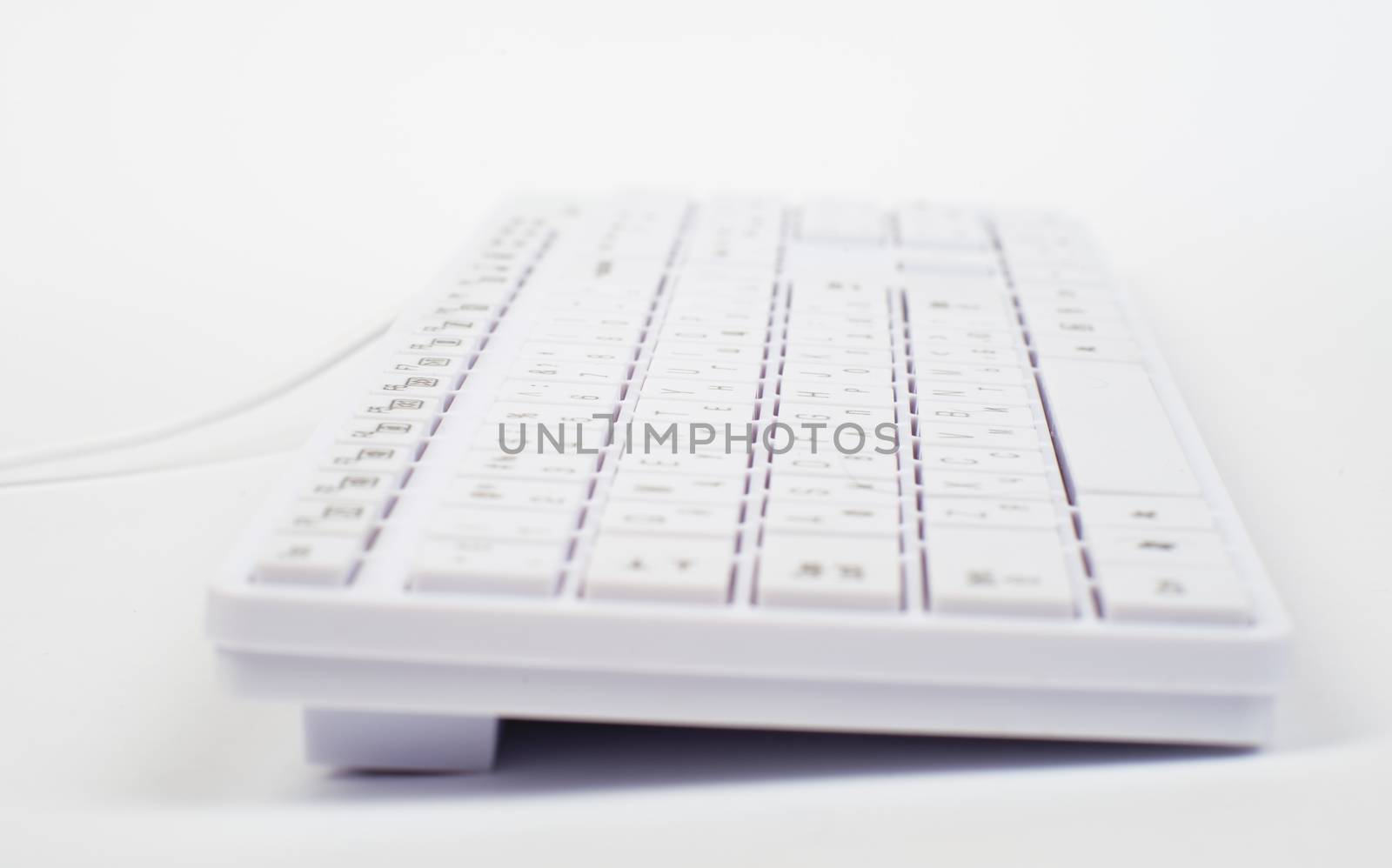 White keyboard with wire on isolated white background, close up view
