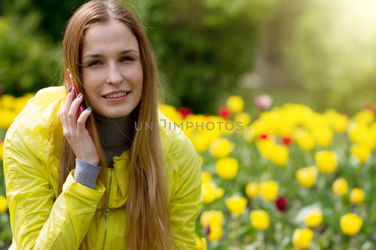 Woman calling on the mobile phone in a green field with yellow flowers