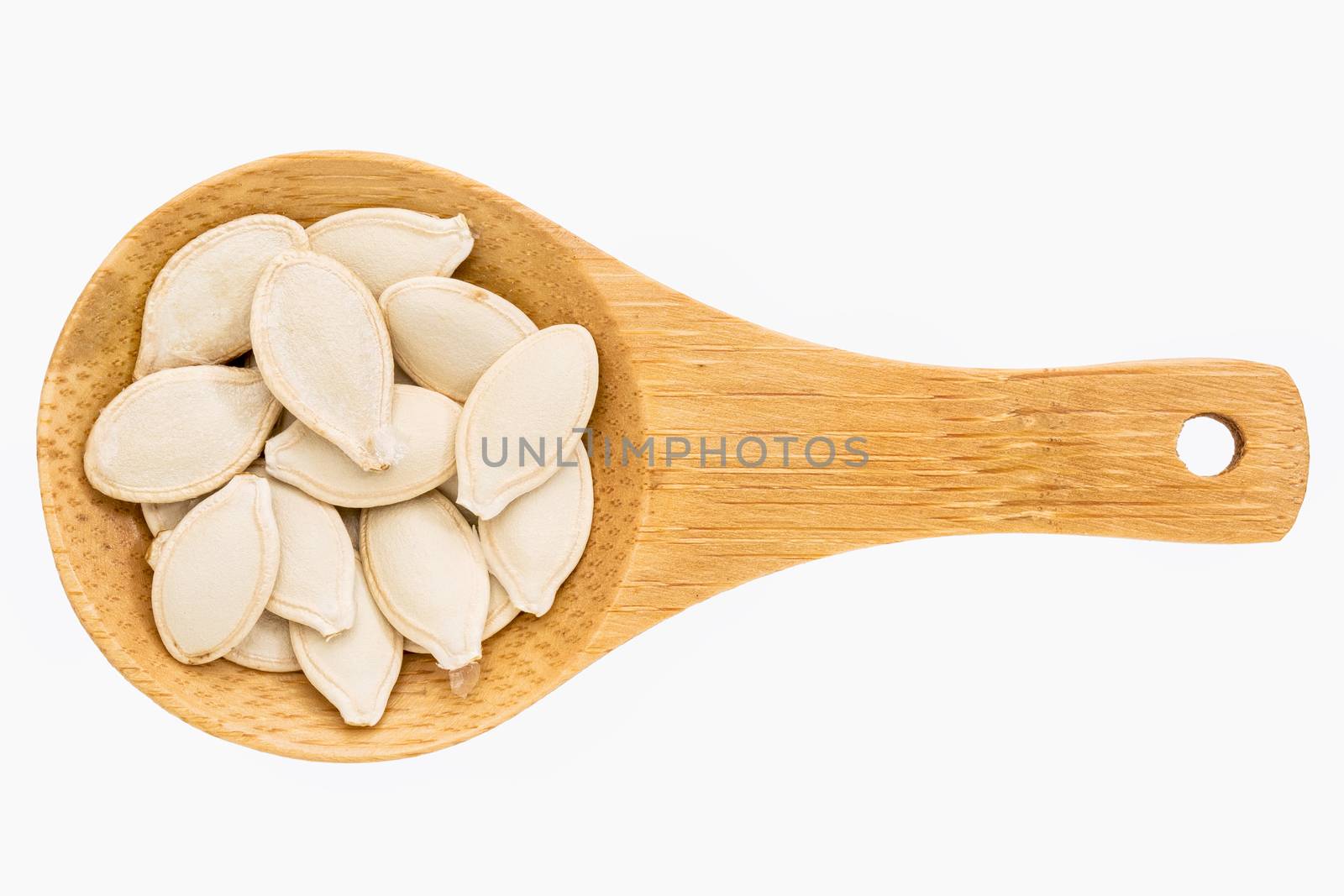 pumpkin seeds on a small wooden spoon isolated on white with a clipping path