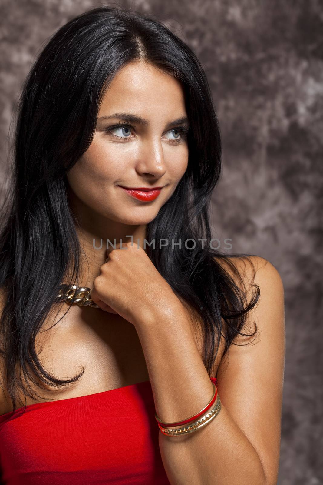 Close up Pretty Young Woman with long Black Hair, Wearing Red. Looking at Right Frame. Captured with Abstract Brown Background.