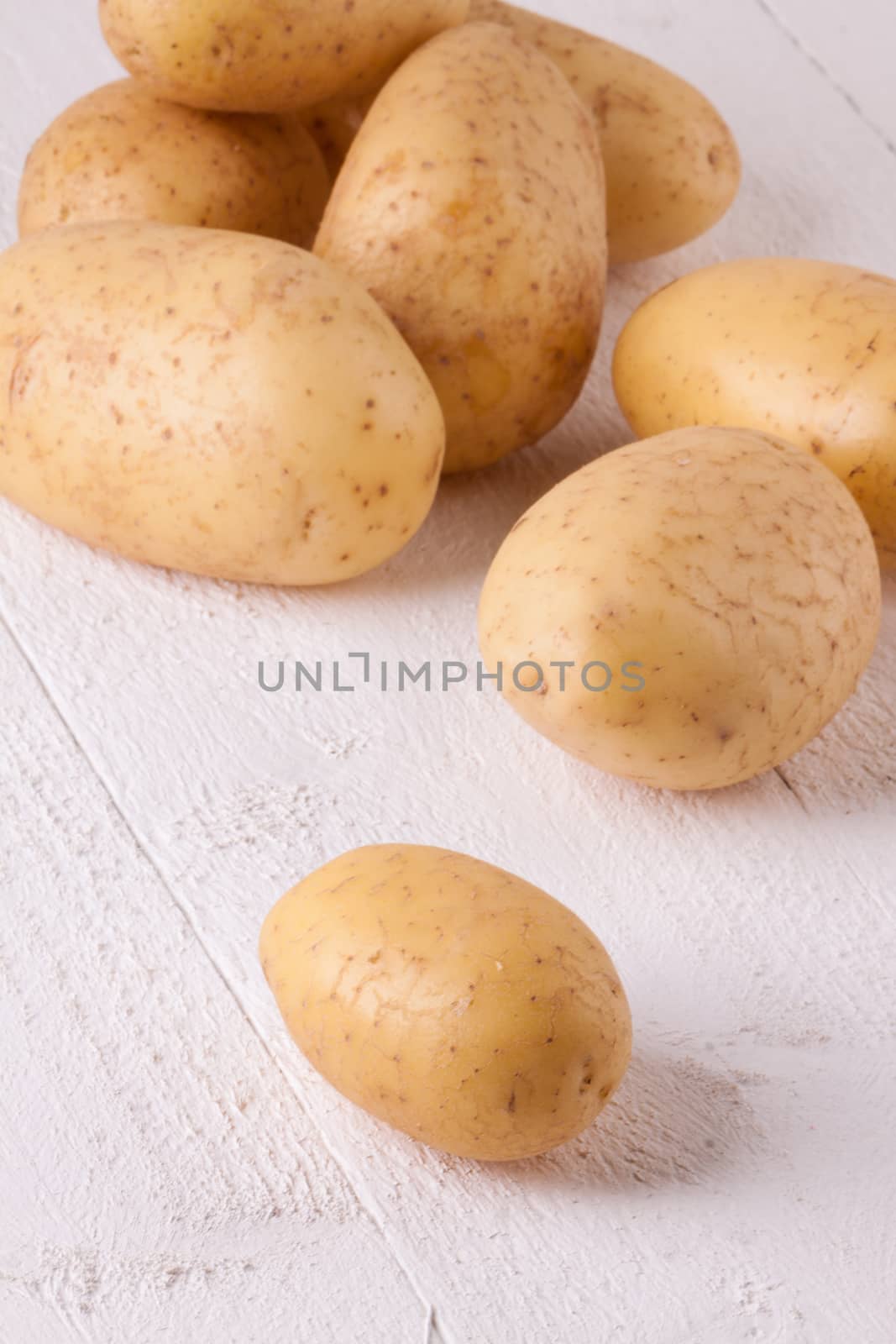 Farm fresh washed whole potatoes for a healthy nutritious cooking ingredient on white painted wooden boards