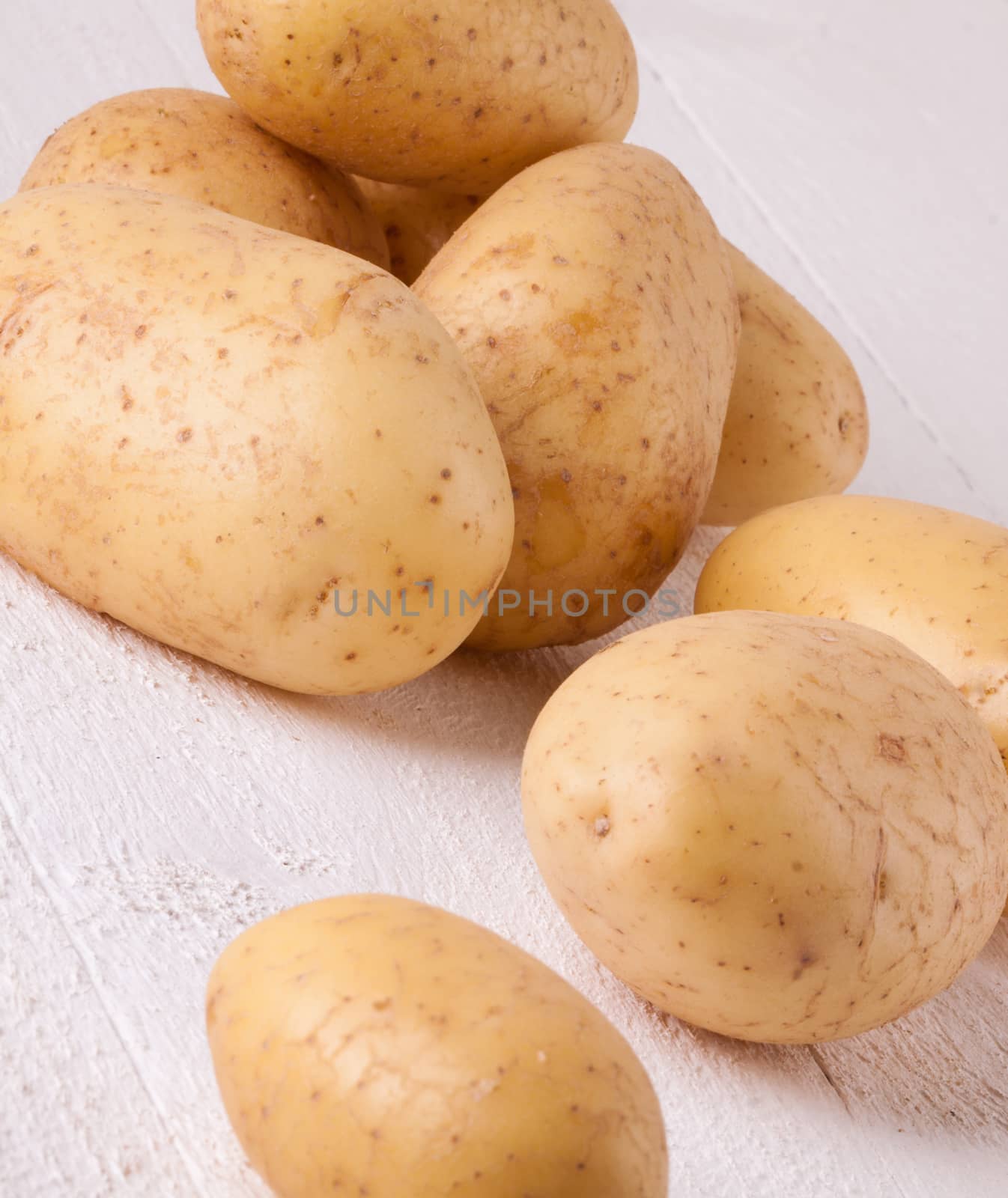 Farm fresh washed whole potatoes for a healthy nutritious cooking ingredient on white painted wooden boards