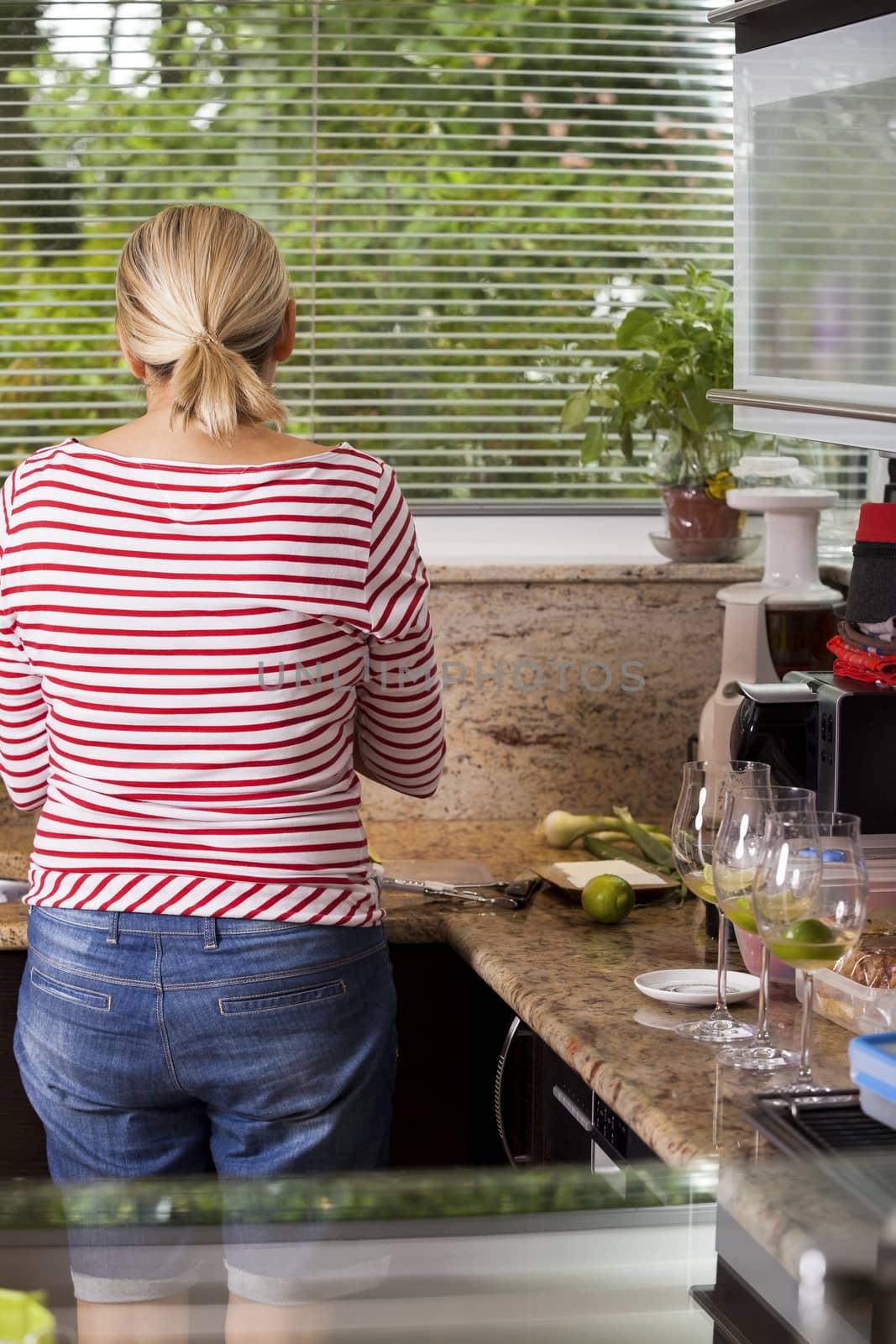 Attractive blond woman barbecuing meat outdoors in the garden grilling two marinated spicy beef steaks over a fire