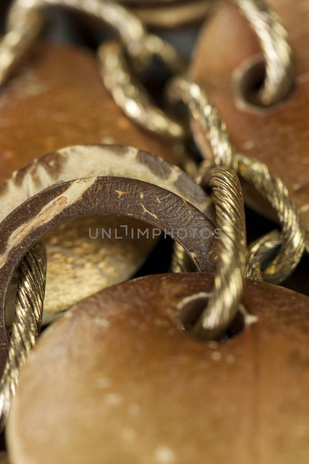 Scratched and tarnished old silver jewellery with two flat discs flanking a ring suspended on an oval link chain, close up view on a grey background