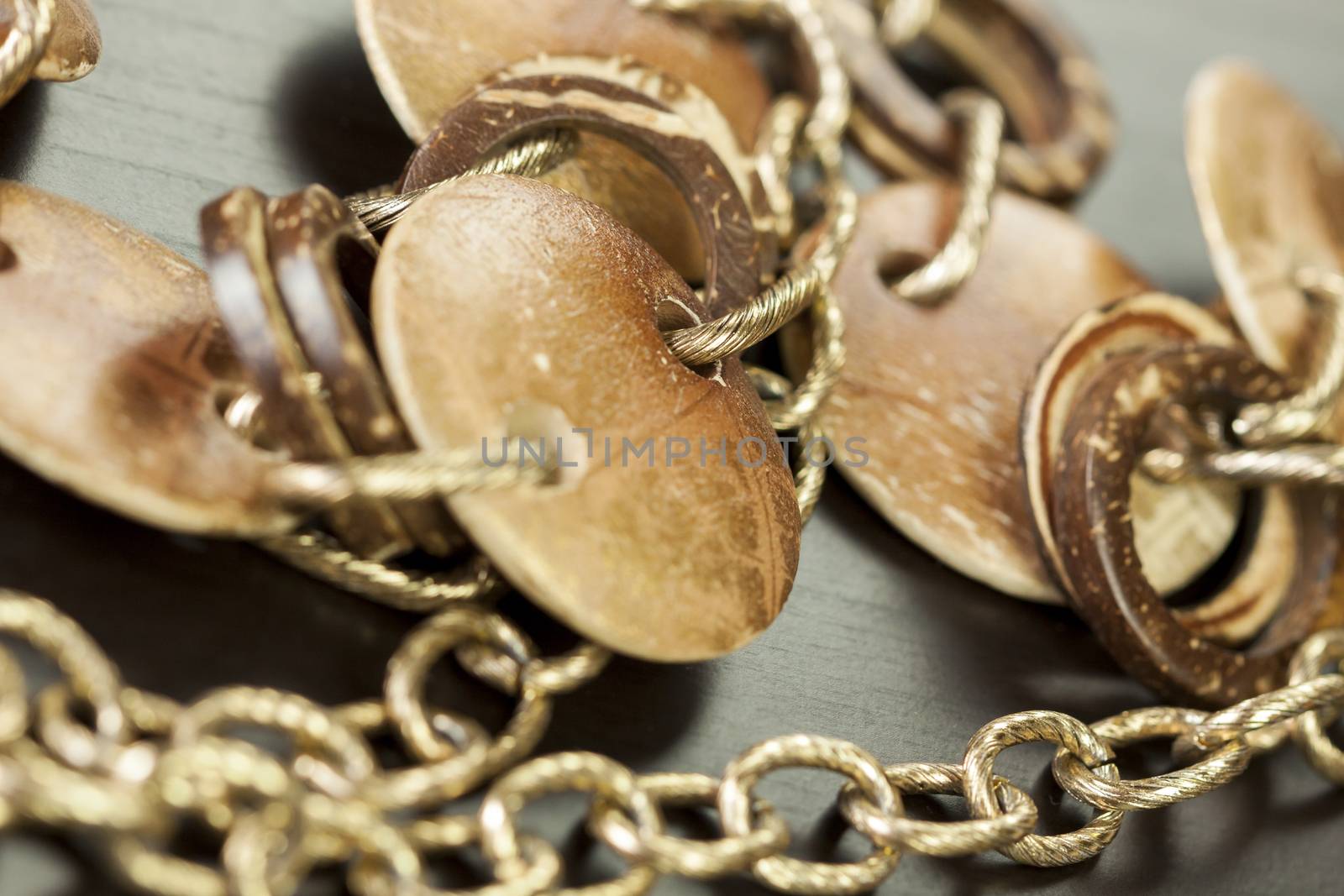 Scratched and tarnished old silver jewellery with two flat discs flanking a ring suspended on an oval link chain, close up view on a grey background