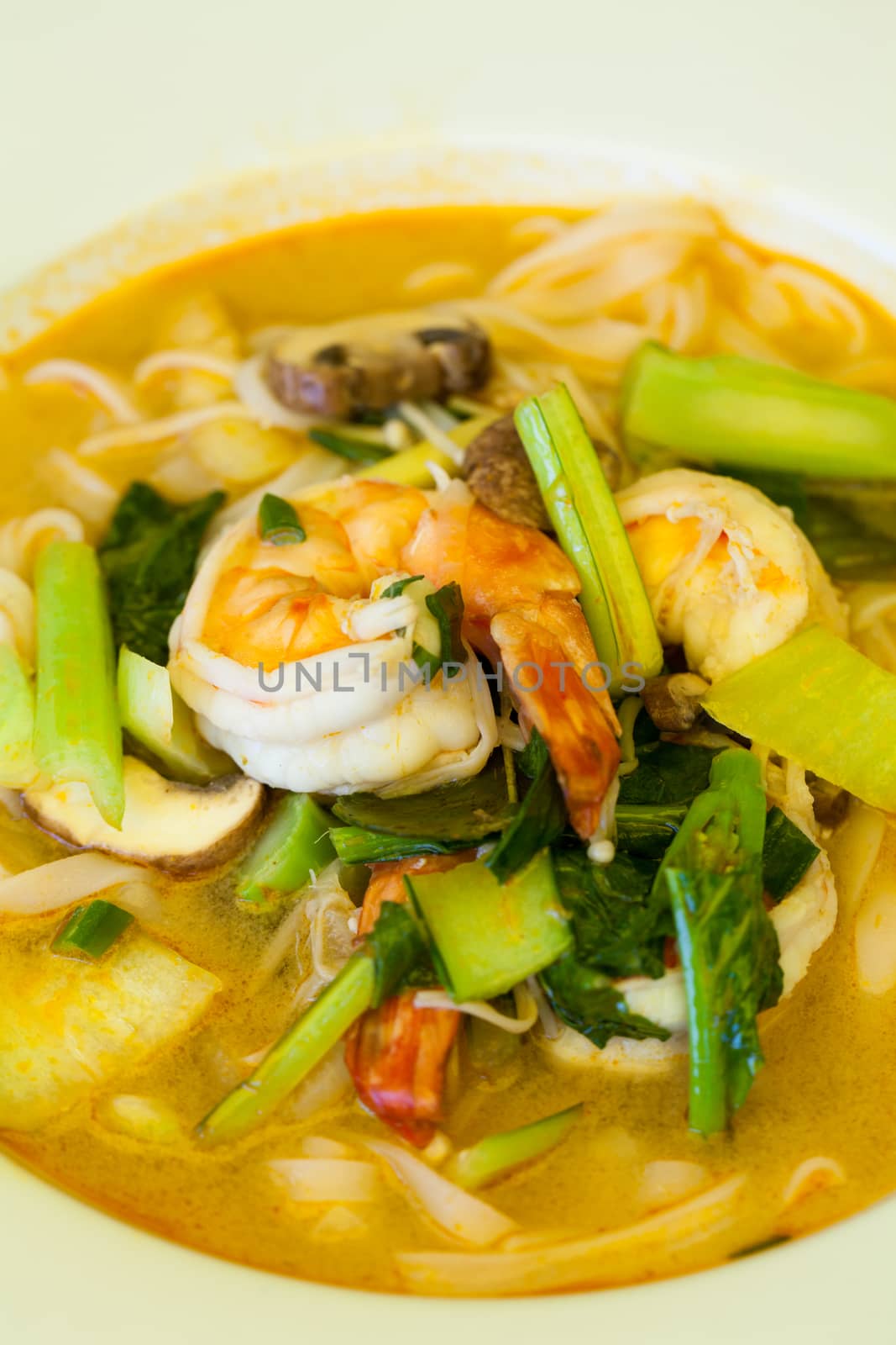 Bowl of traditional Thai tom yam soup with vegetables and prawns in a spicy aromatic broth served with chopsticks