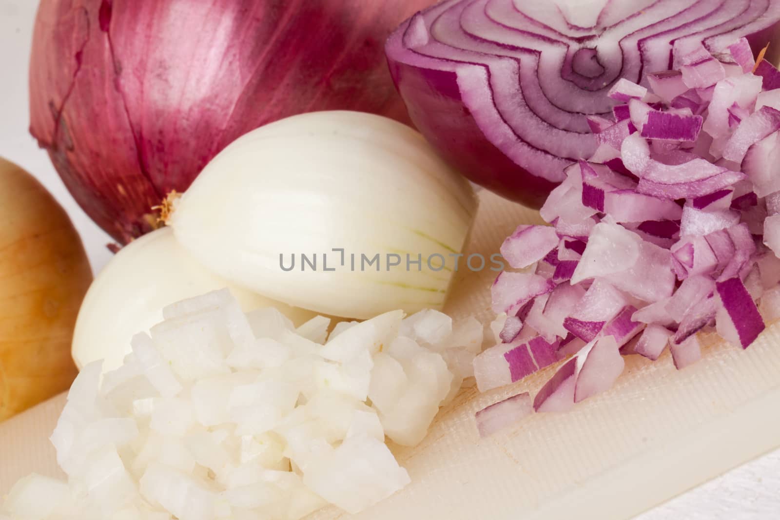 Whole, peeled and diced brown or white onion ready for use as a pungent aromatic flavoring in cooking on a white background