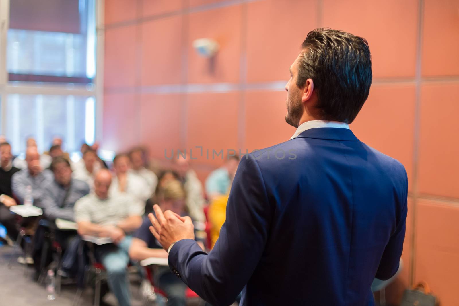 Speaker at Business Conference with Public Presentations. Audience at the conference hall. Entrepreneurship club. Rear view. Horisontal composition. Background blur.