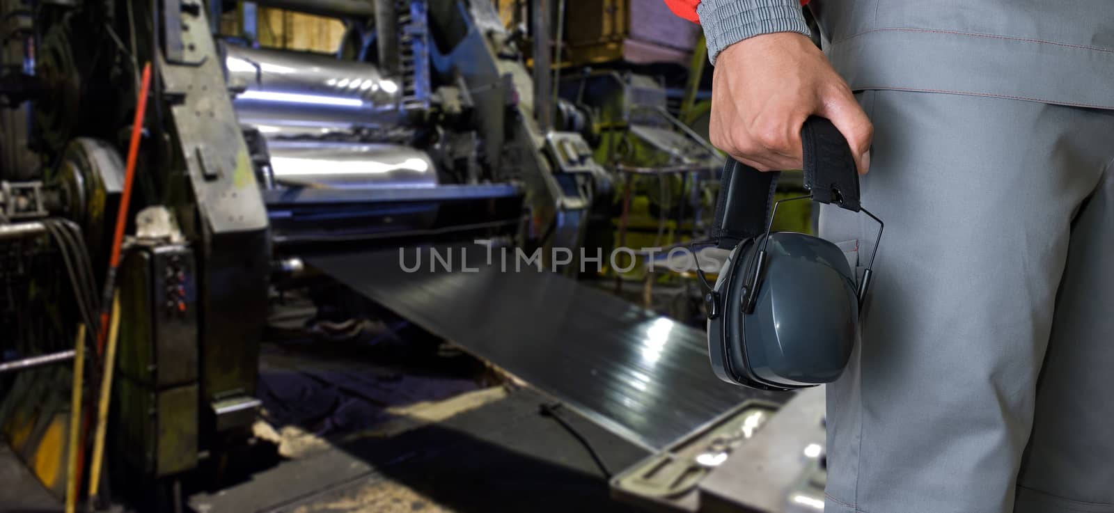 Worker with protective headphone at man hands at industrial factory