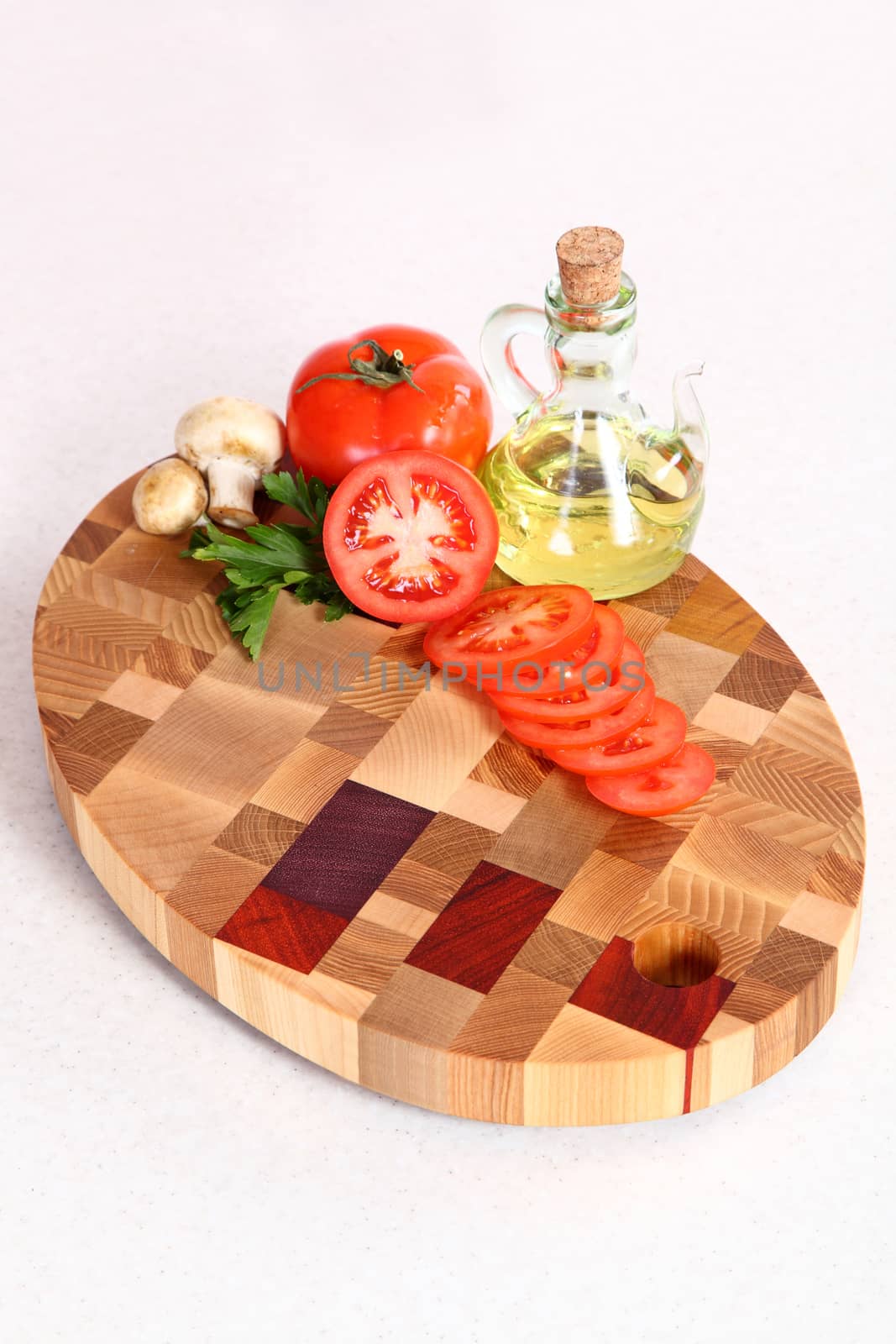 the cut tomato, vegetable oil and field mushrooms on a chopping board