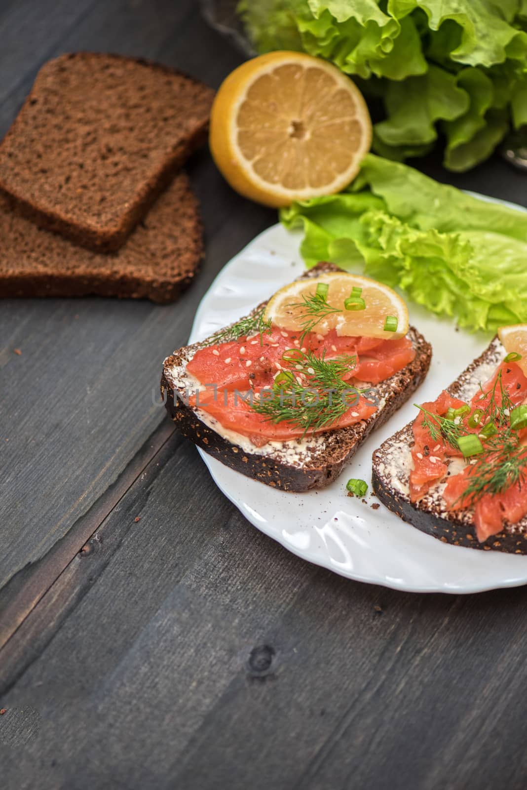 Homemade sandwich with salmon and rye bread , butter lemon, and lettuce for breakfast
