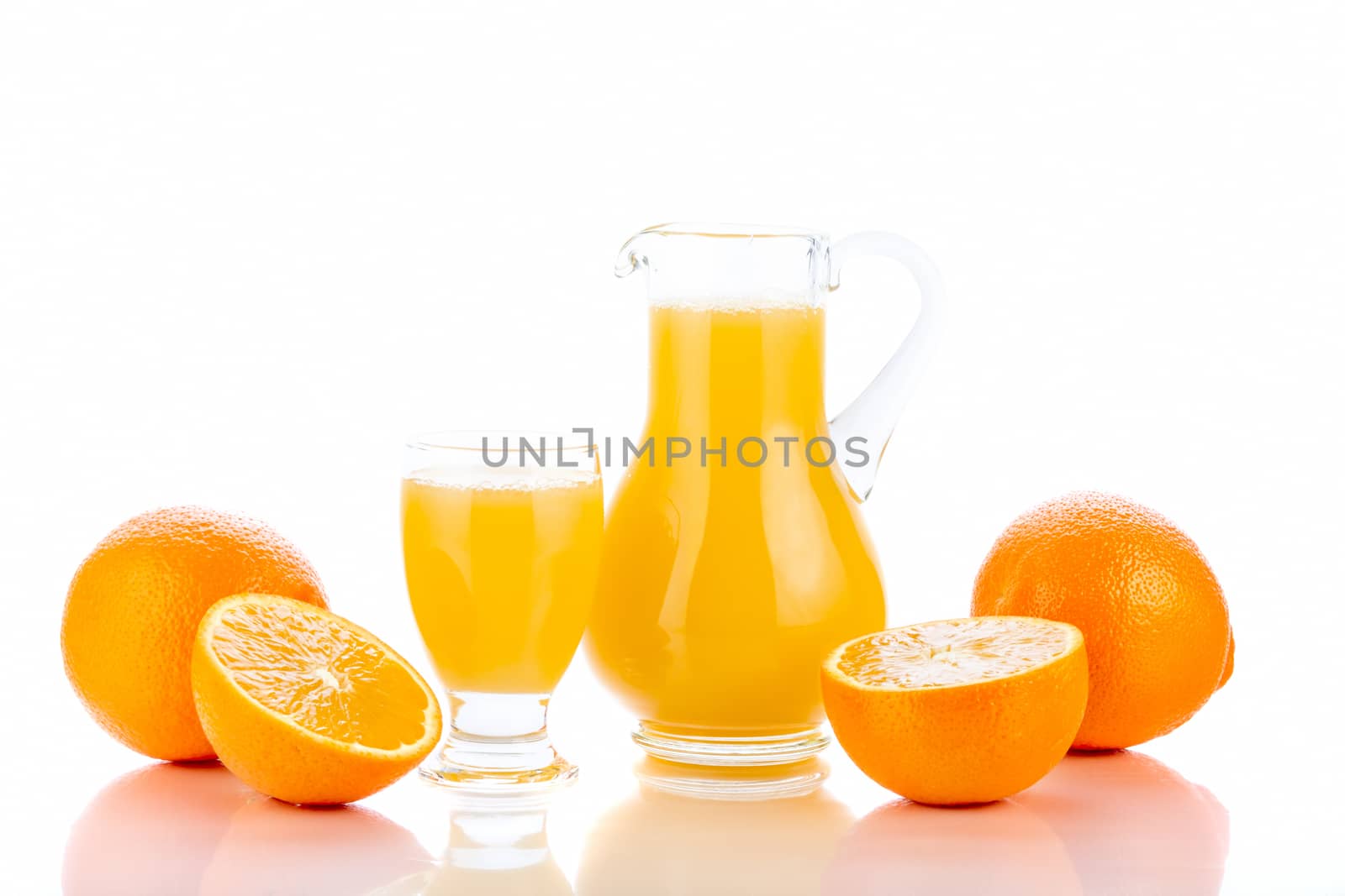 Orange juice in pitcher and oranges. Isolated on white background