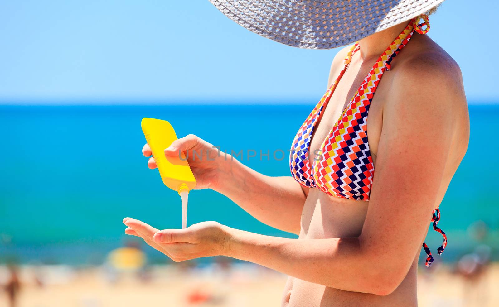 woman applying protective lotion before sunbathing at beach