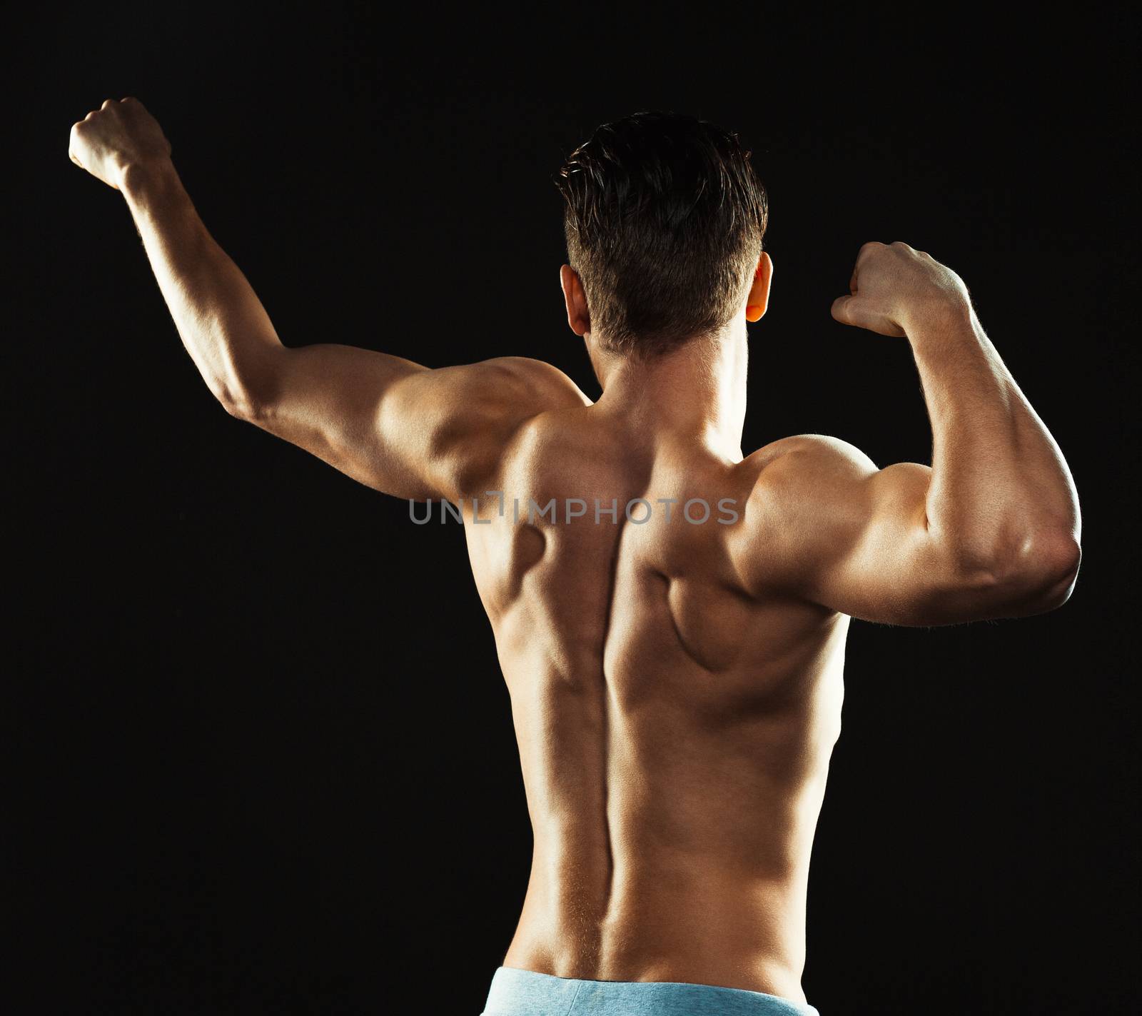 Athletic man showing his back on the black background by vlad_star