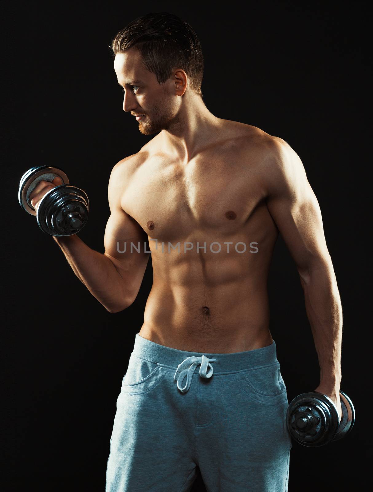Athletic attractive man with dumbbells on the black by vlad_star